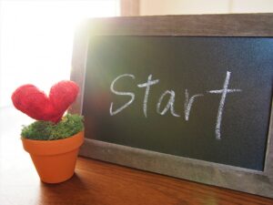 黒板に書かれたSTARTの文字とハート型の赤い花