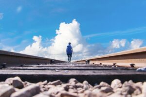 青空を背景に線路を歩く男性