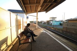 夕暮れのプラットフォームで電車を待つ男性