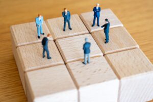 積み木の上で議論するスーツ姿の男性たち