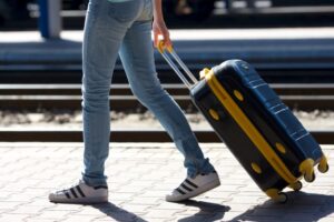 スーツケースを引いて歩くデニムを履いた人物